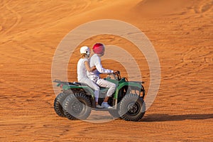 Quad Biking Dubai Adventure Tour Ã¢â¬â Young copule of tourists having fun on Quad Bike Riding in dunes of Dubai